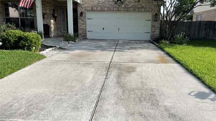 Dirty, stained concrete driveway before pressure washing in Tomball, TX